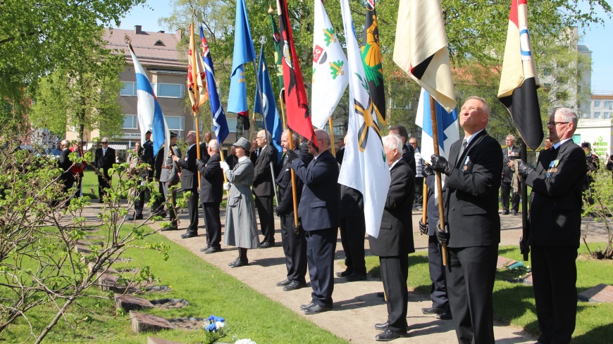 Kaatuneitten muistopäivän viettäjiä Lappeenrannan sankarihautausmaalla lippujen kanssa.